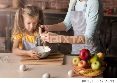 Involved daughter breaking eggs with her mother in Involved daughter breaking eggs with her mother in 25735144