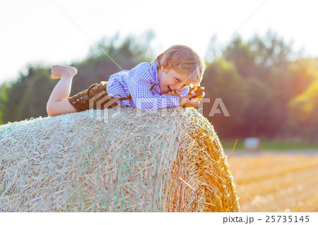little kid boy lying on hay stack and smiling little kid boy lying on hay stack and smiling 25735145