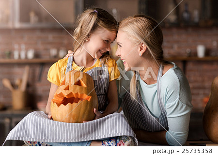Smiling girl holding jack o lantern sitting near 25735358