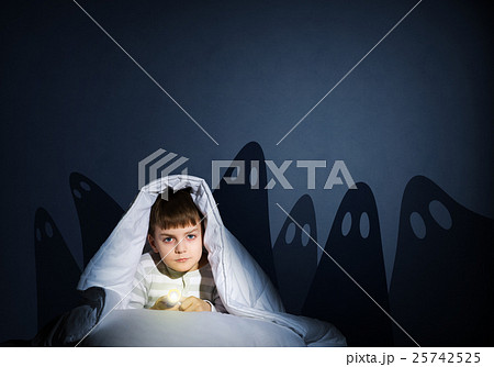 boy under the covers with a flashlight 25742525