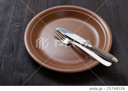 brown plate with parallel knife, spoon on dark 25748526