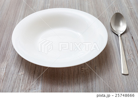 white deep plate and spoon on gray brown board 25748666