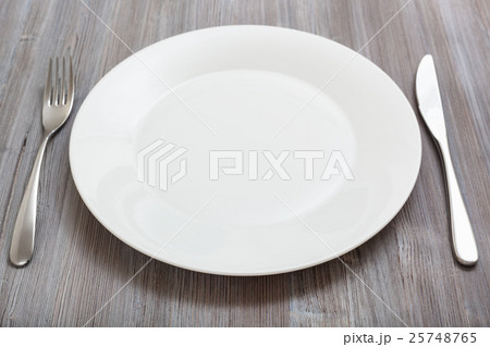 white plate, knife, spoon on gray brown table 25748765