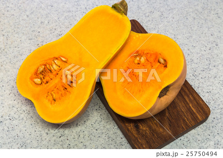 Squash cut in half on a wooden board 25750494