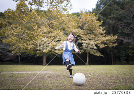 秋の公園でサッカーボールで遊ぶ女の子の写真素材