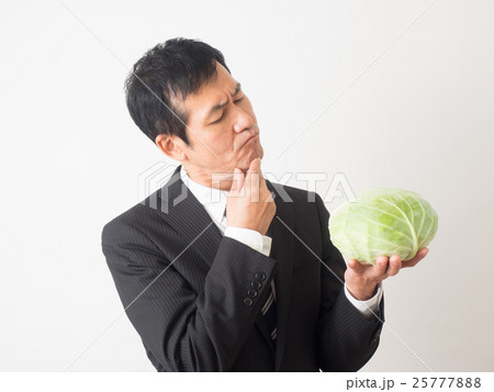 不安そうな表情でキャベツを持つビジネスマン 25777888