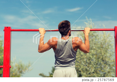 young man exercising on horizontal bar outdoors young man exercising on horizontal bar outdoors 25787569