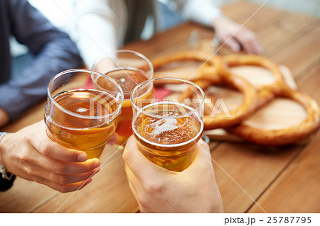 close up of hands clinking beer at bar or pub 25787795