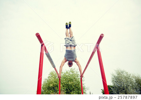 young man exercising on parallel bars outdoors 25787897