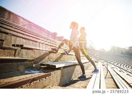 couple stretching leg on stands of stadium 25789223