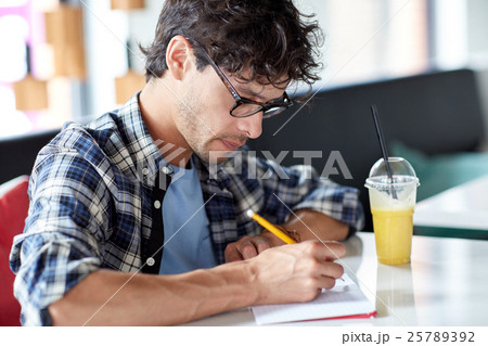 man with notebook and juice writing at cafe man with notebook and juice writing at cafe 25789392