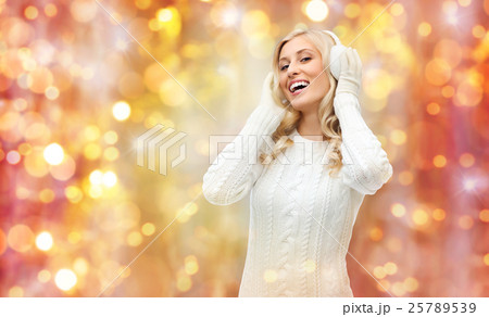 smiling young woman in winter earmuffs and sweater smiling young woman in winter earmuffs and sweater 25789539