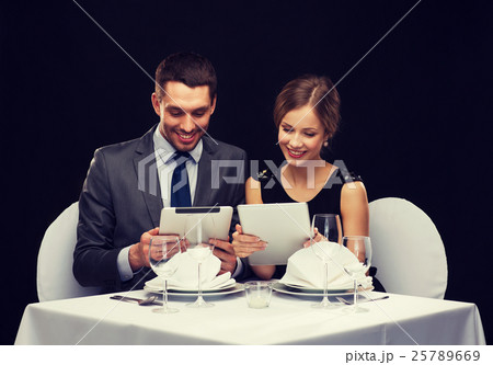 couple with menus on tablet pc at restaurant couple with menus on tablet pc at restaurant 25789669