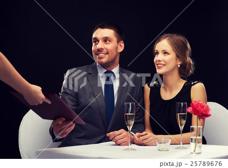 waiter giving menu to happy couple at restaurant waiter giving menu to happy couple at restaurant 25789676