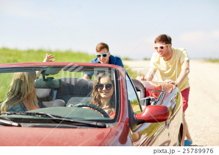 happy friends pushing broken cabriolet car 25789976