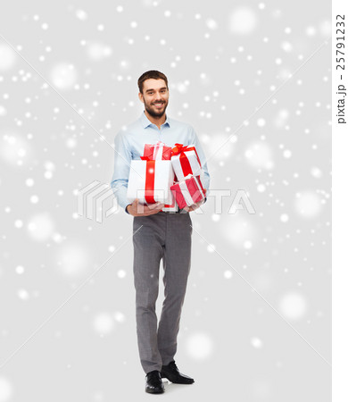 happy young man holding christmas gifts over snow happy young man holding christmas gifts over snow 25791232