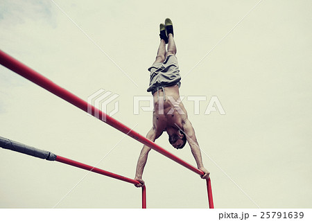 young man exercising on parallel bars outdoors 25791639