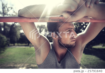 young man exercising on horizontal bar outdoors 25791640