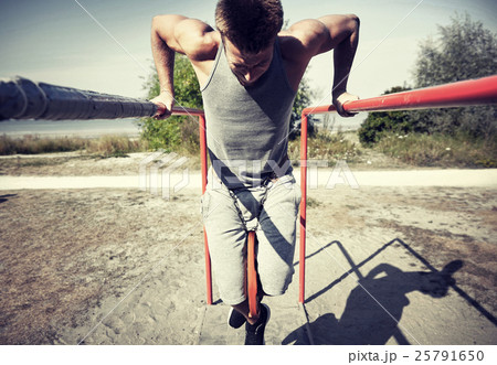young man exercising on parallel bars outdoors 25791650