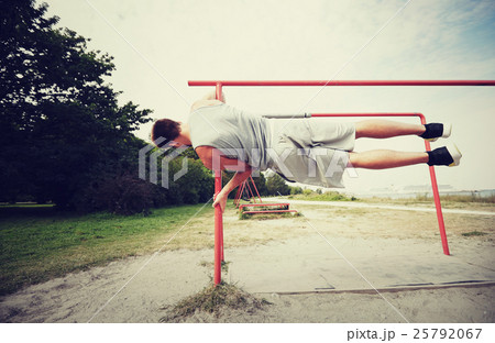 young man exercising on parallel bars outdoors 25792067