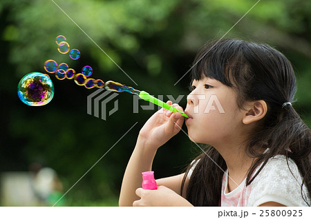 シャボン玉で遊ぶ女の子の写真素材