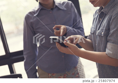 women look at mobile phone in meeting room 25807974