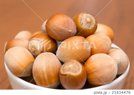 Nuts in a white plate on a wooden table. Hazelnuts. Nuts in a white plate on a wooden table. Hazelnuts. 25834476