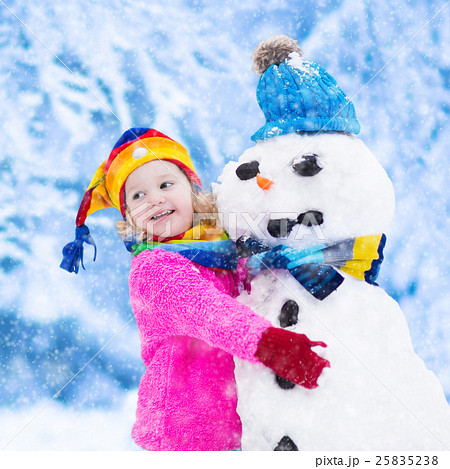 Little girl building a snow man in winter Little girl building a snow man in winter 25835238