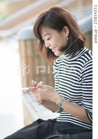 屋外でスマホを触るミドル女性 25854351