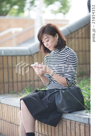屋外でスマホを触るミドル女性 25854352