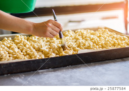 Hand with brush touches dough. Hand with brush touches dough. 25877584