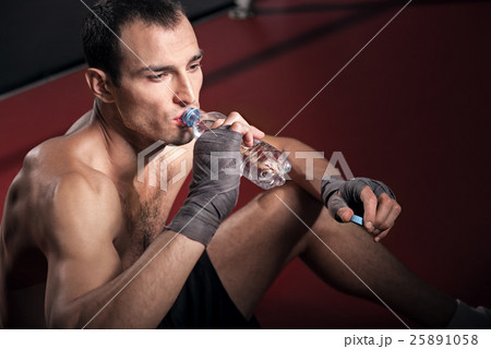 Handsome trainer sitting on floor and drinking Handsome trainer sitting on floor and drinking 25891058