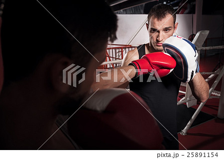 Young trainer holding boxing pad Young trainer holding boxing pad 25891154