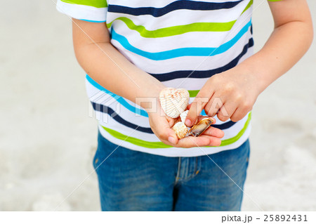 Little kid boy having fun with collecting shells Little kid boy having fun with collecting shells 25892431