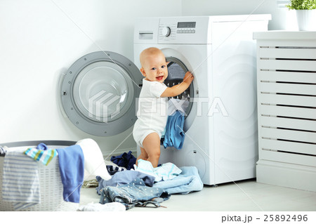 happy baby boy to wash clothes and laughs in laundry happy baby boy to wash clothes and laughs in laundry 25892496