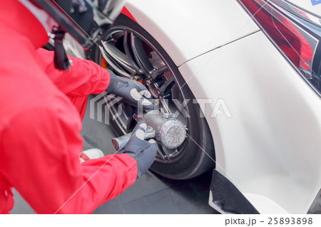 Auto mechanic changing racing car wheel 25893898