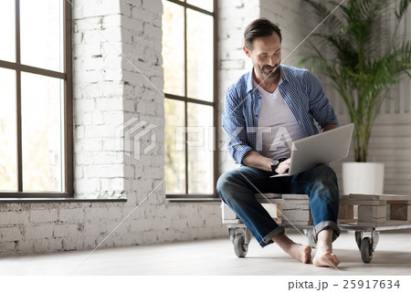Positive delighted man holding a laptop on his 25917634
