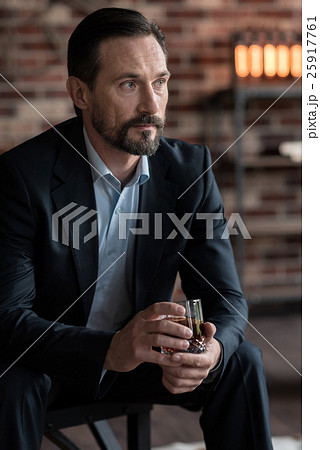 Thoughtful successful businessman holding a glass Thoughtful successful businessman holding a glass 25917761