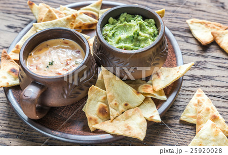 Bowls of guacamole and queso with tortilla chips 25920028