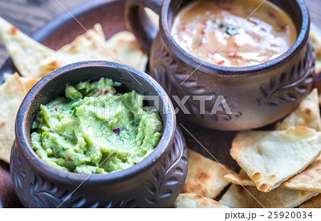 Bowls of guacamole and queso with tortilla chips Bowls of guacamole and queso with tortilla chips 25920034