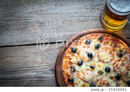 Cooked pizza with a glass of beer 25920091