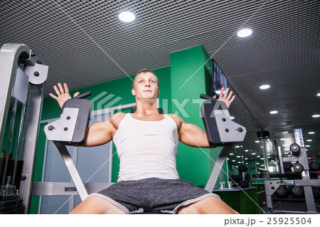 Athlete doing chest exercise on machine in gym 25925504