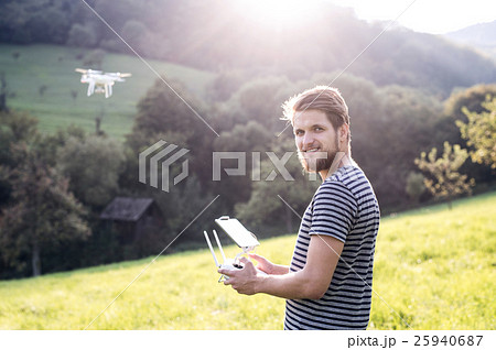 Young hipster man with flying drone. Sunny green 25940687