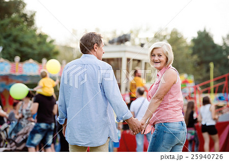 Senior couple at the fun fair, holding hands Senior couple at the fun fair, holding hands 25940726
