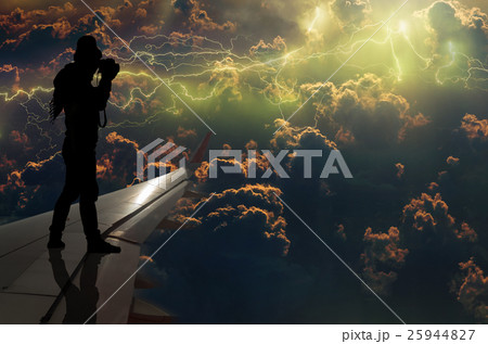 silhouette of man who taking photo of the thunder lightnings over the clouds and storm on airplane wing, Challenge business concept 25944827