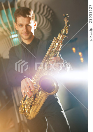 Young man in a suit standing with saxophone Young man in a suit standing with saxophone 25955527