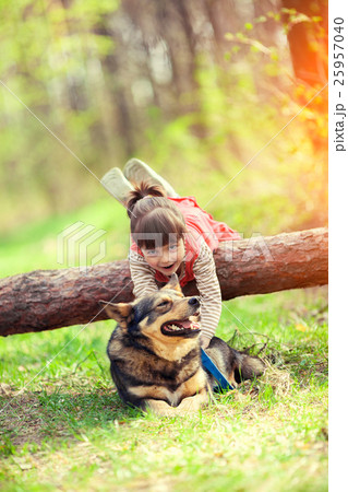 Happy little girl playing with dog in the forest Happy little girl playing with dog in the forest 25957040