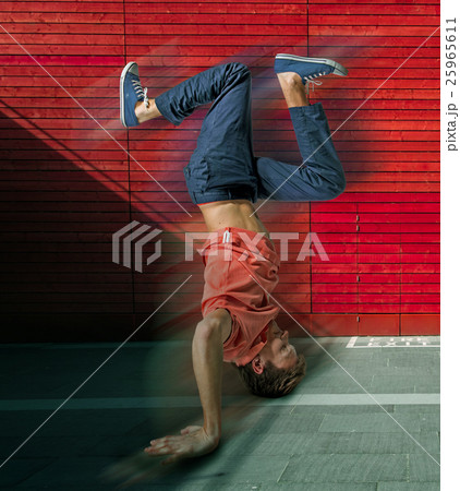 Break dancer doing handstand against colorful wall 25965611