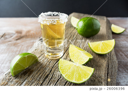 Tequila shot with lime on rustic wooden background Tequila shot with lime on rustic wooden background 26006396