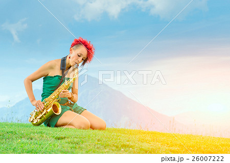 Young saxophonist (woman with the red hair) playing saxophone in Young saxophonist (woman with the red hair) playing saxophone in 26007222
